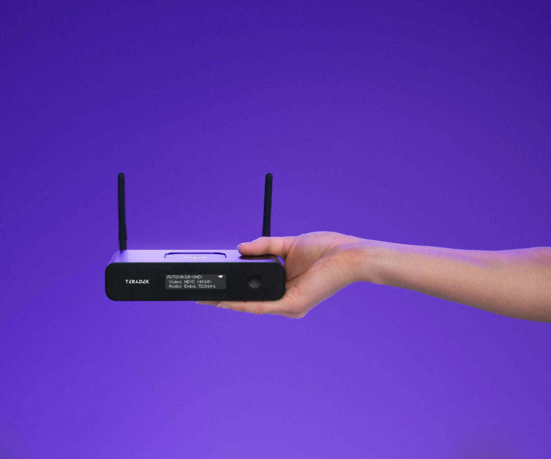 Woman's hand holding out a Teradek encoder against a purple background
